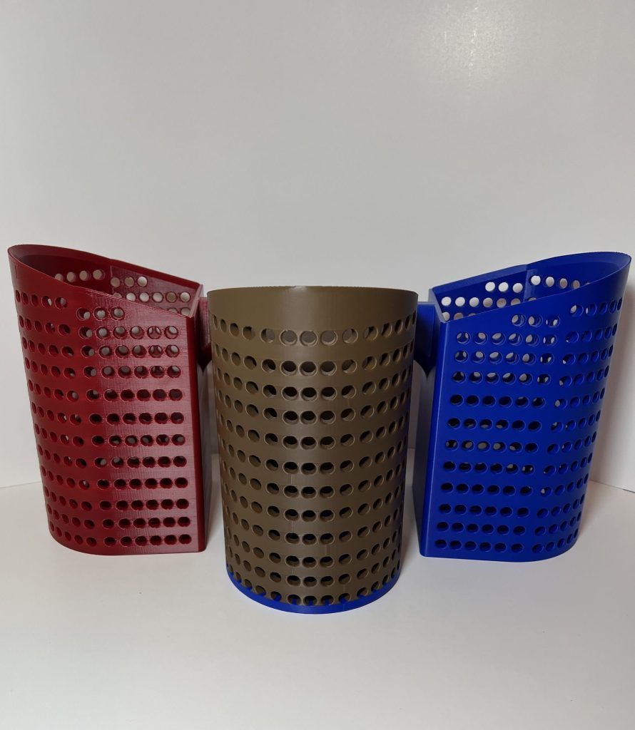 Three perforated 3D-printed sand scoops in red, tan, and blue.